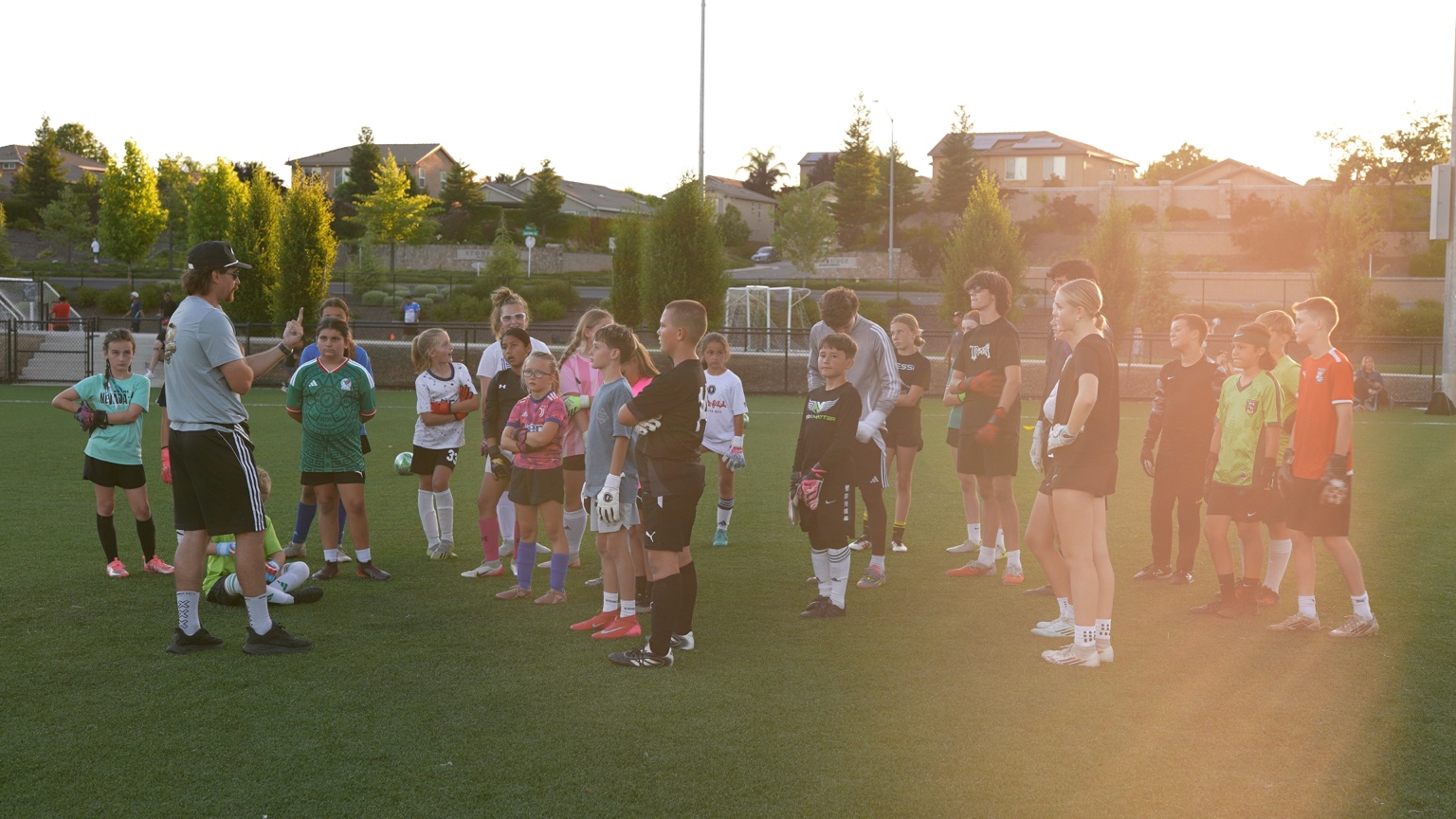 Coach speaking with a group of youth goalkeepers on the field